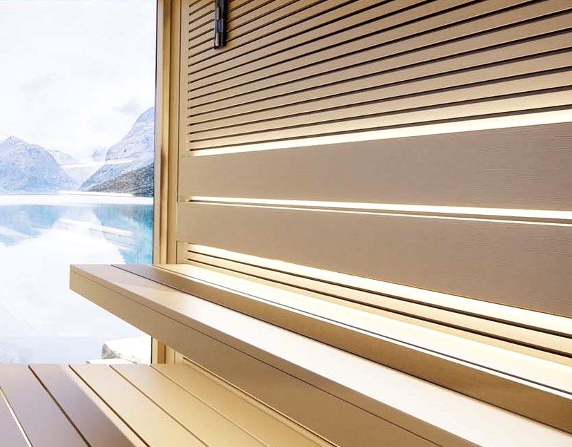 Gerade Saunabank aus hellem Holz mit unterer Stufe, dahinter Lamellenwand und Fenster zum Bergsee