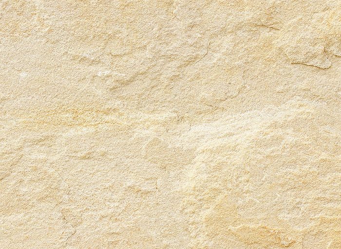 Sandfarbene Natursteinfliese mit rauer, gespaltener Oberfläche, Nahaufnahme von oben