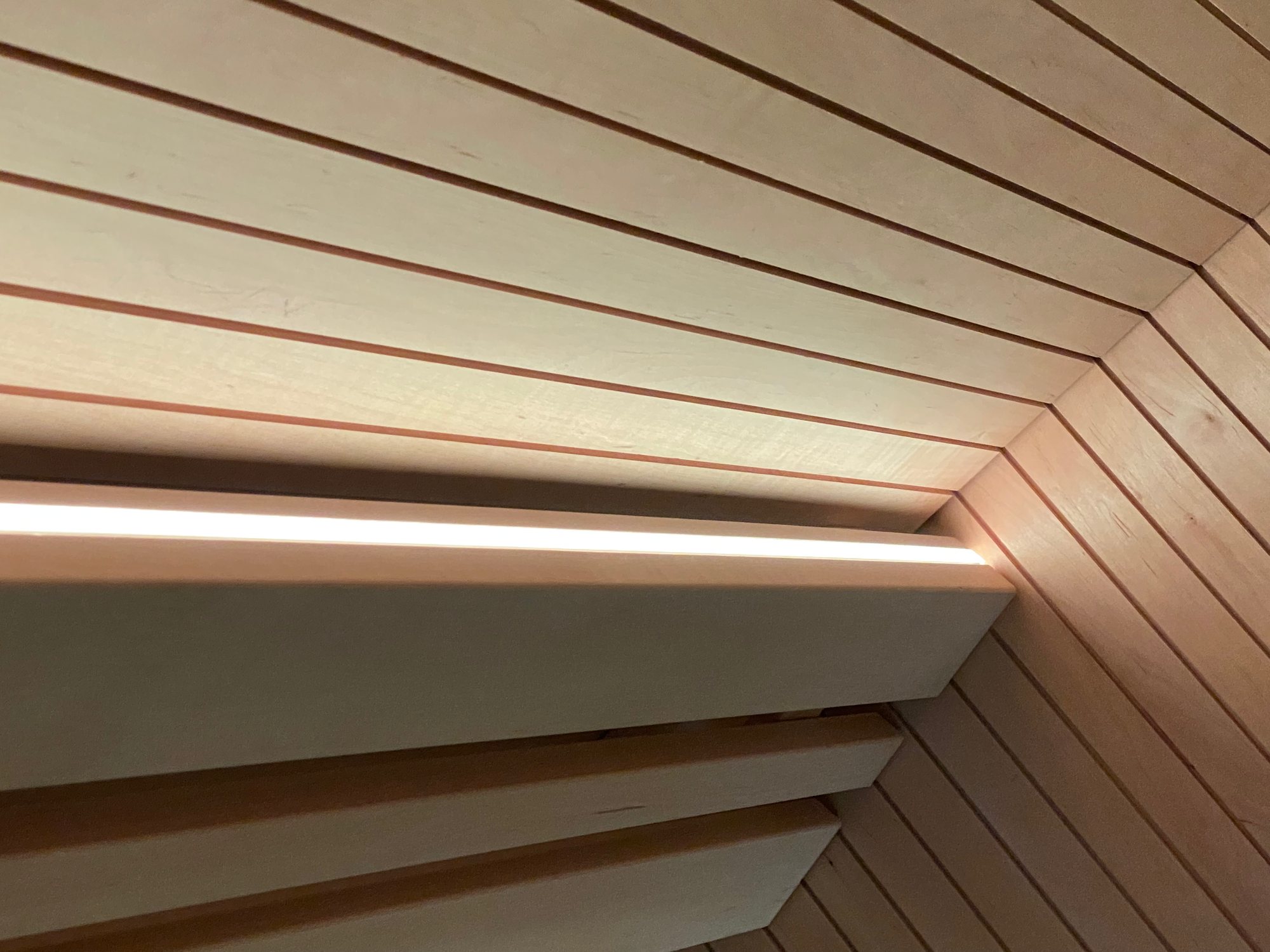 Lichtfuge unter einer Saunabank aus hellem Holz