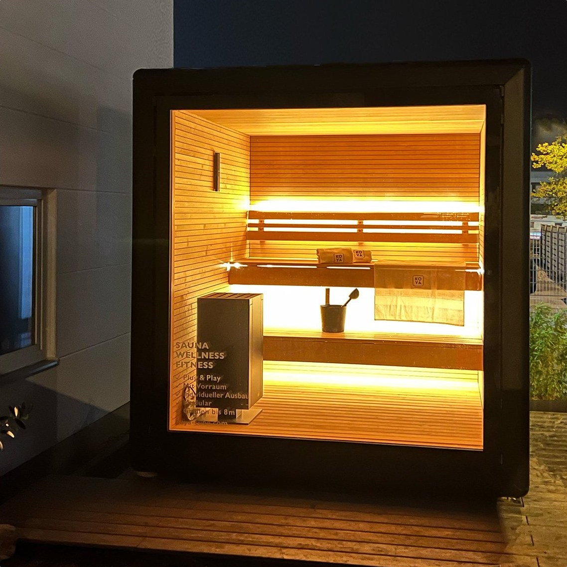 Blick durch die Glasfront auf Bänke, Ofen und Lichtfugen
