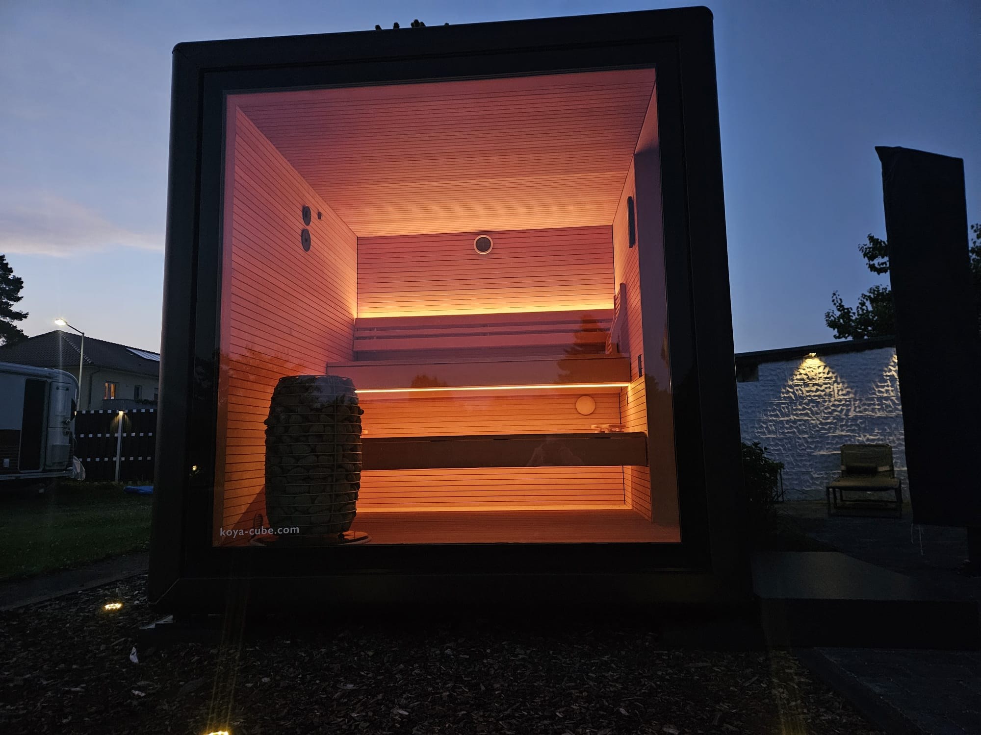 Aufnahme: gebaute KOYA Sauna in der Abenddämmerung, innen orange beleuchtet